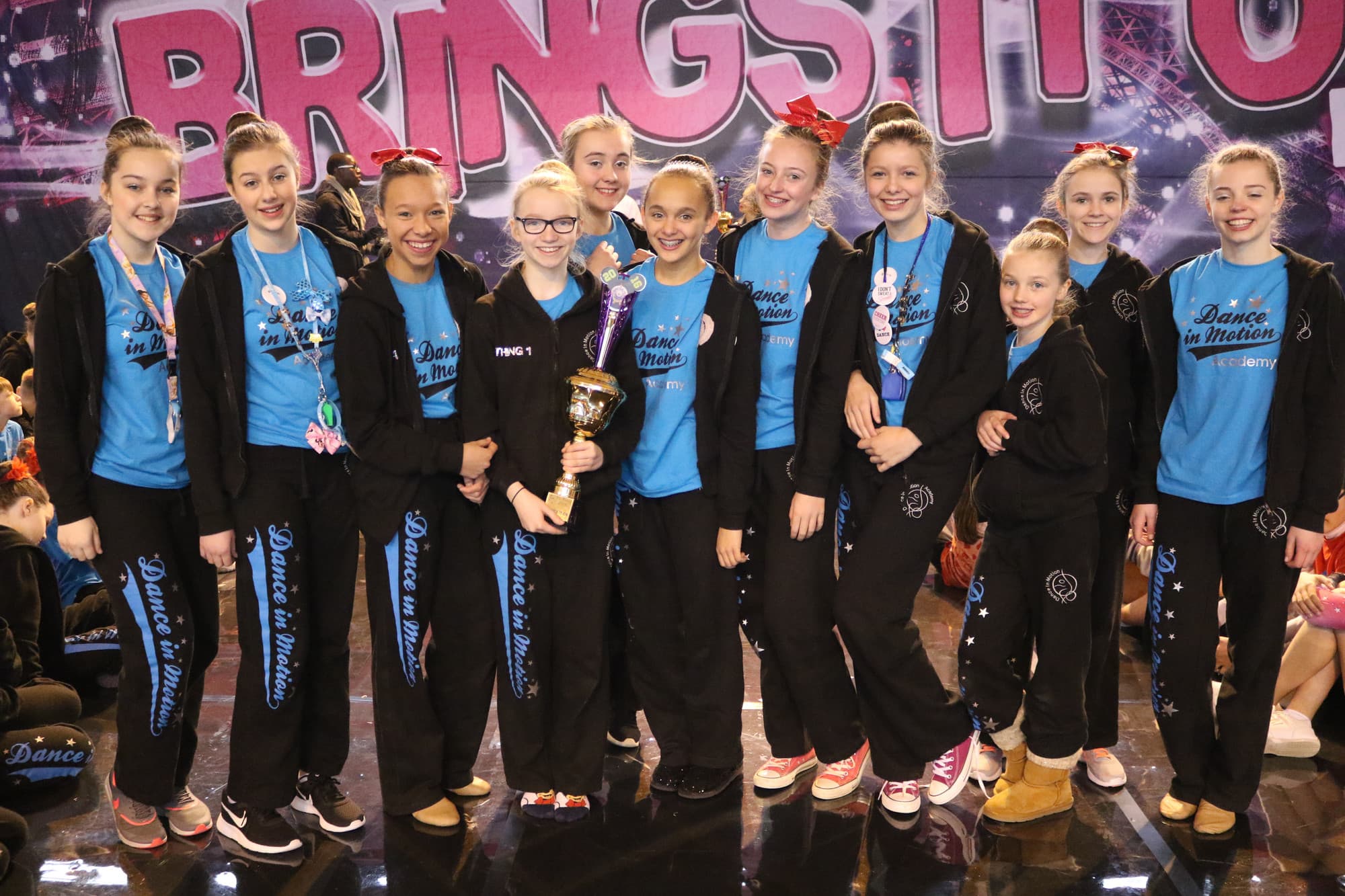 Dance in Motion Academy students celebrating with a trophy on stage