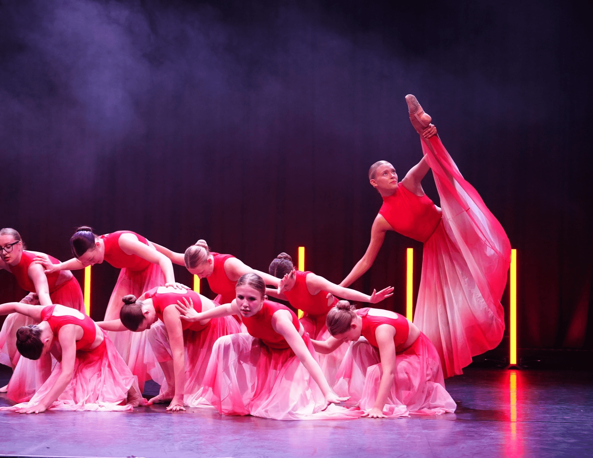 Dance in Motion Academy dancers performing on stage in red ombre costumes
